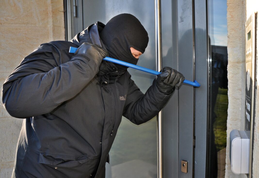Een inbreker probeert een deur open te forceren